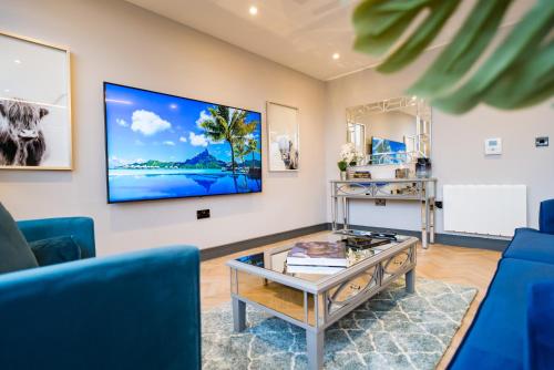 a living room with blue chairs and a tv on the wall at Luxe Apartments, The Moorwell, Secure Parking, - 10mins Cardiff City Ctr in Cardiff