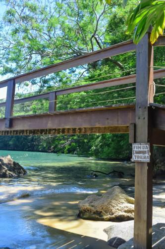 a bridge over a river with a sign on it at Hostel MPB Ilha Grande in Abraão