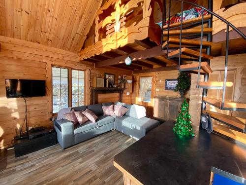 a living room with a couch and a staircase in a cabin at Le petit chalet sur le lac in Sainte-Marguerite