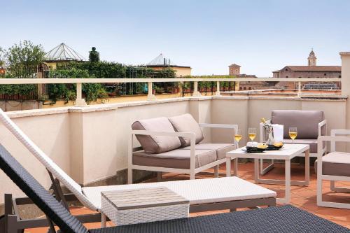 a patio area with chairs, tables, and a balcony at Rome Times Hotel in Rome