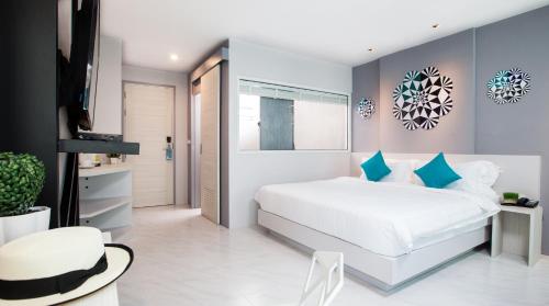 a bedroom with a white bed with blue pillows at The Crib Patong - SHA Certified in Patong Beach