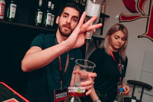 a man holding a drink in front of a woman at Let's Rock Party Hostel in Kraków