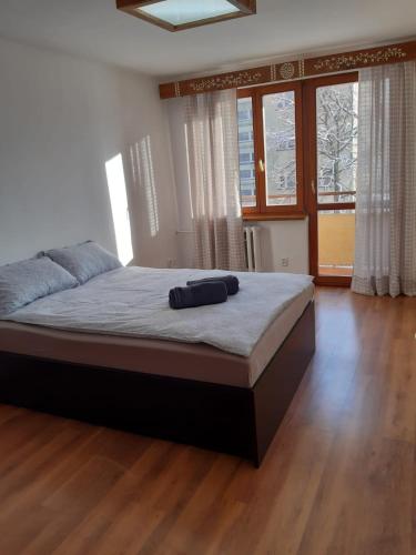 a large bed in a bedroom with wooden floors and windows at Na Równi in Zakopane