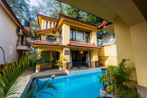 a house with a swimming pool in front of a house at VILLA M - LAGOON 4 CALANGUTE GOA 3BHK, Pool Facing, Near Beach, Free Breakfast, Free WIFI and Well Located in Old Goa