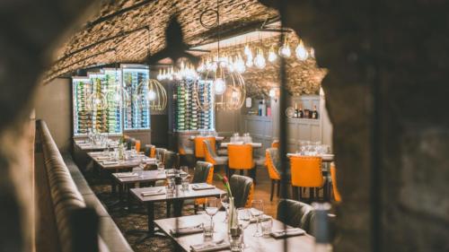 a dining room with tables and chairs and chandeliers at The Bear, Cowbridge in Cowbridge