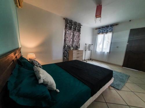 a bedroom with a green bed with a pillow on it at L'auberge de l'île : chambres d'hôtes in Dzaoudzi