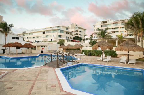 a swimming pool with umbrellas and a resort at Brisas Shores Penthouse Beachfront, Ocean View Terrace Cancun Hotel Zone, 2 bedrooms in Cancún