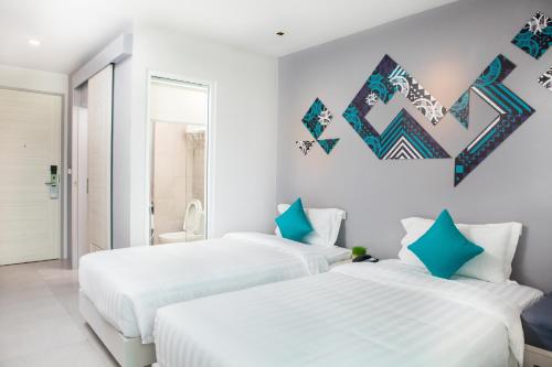 two beds in a white room with blue accents at The Crib Patong - SHA Certified in Patong Beach