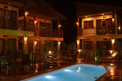 a swimming pool in front of a hotel at night at Pousada Rosa Maria in Praia do Rosa