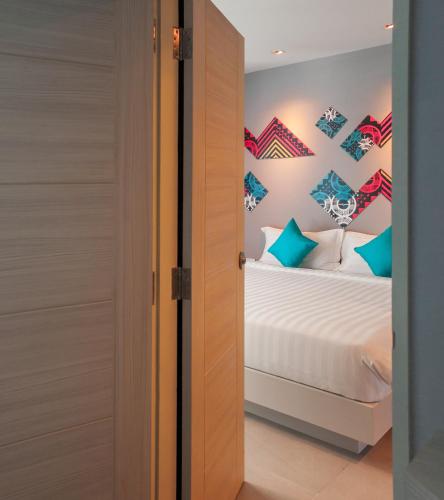 a bedroom with a bed with blue and green pillows at The Crib Patong - SHA Certified in Patong Beach