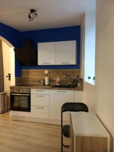 une cuisine avec des armoires blanches et un mur bleu dans l'établissement Le Montréalais, à Montréal