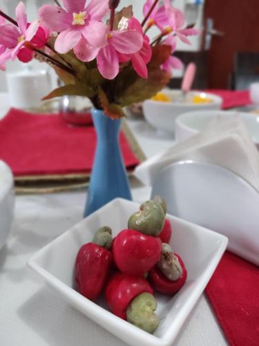 a white bowl of fruit and flowers in a blue vase at Hostel Portal Das Fadas in Cavalcante