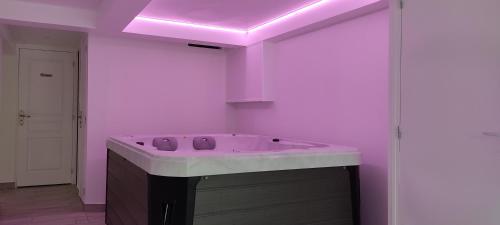 y baño con bañera con iluminación púrpura. en Maison de vacances avec Spa et sauna à Commequiers, 12 à 14 personnes en Commequiers
