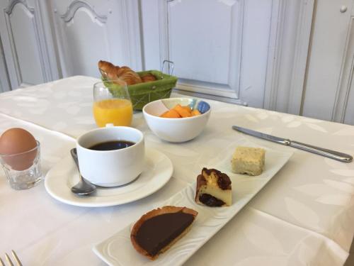 a table with a plate of desserts and a cup of coffee at Hôtel De France - Restaurant L'insolite in Douarnenez