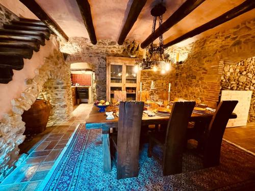 a dining room with a table and a stone wall at Casa de campo del S.XVII in Cruïlles