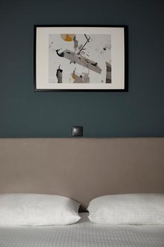 a picture hanging above a bed with a white pillow at Athens21 in Athens