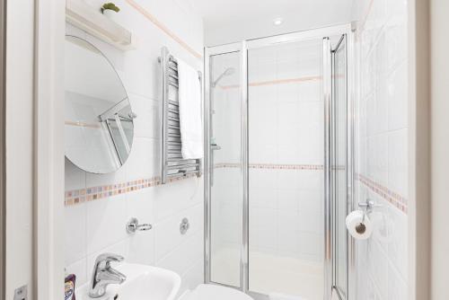 a white bathroom with a shower and a sink at Skyvillion - Station Road Apartment with Balcony & Parking in New Barnet