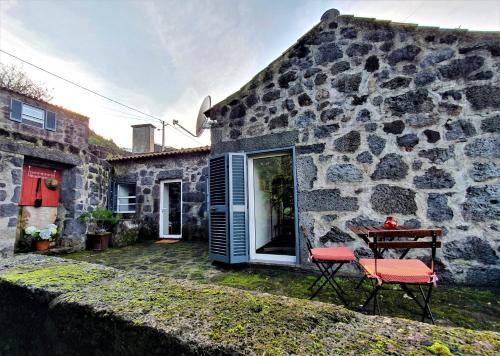 een stenen huis met een tafel en stoelen ervoor bij Casa do Arcanjo in São Roque do Pico