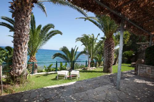 a view of the ocean from a resort with palm trees at Grekis Beach Hotel and Apartments in Petalidhion