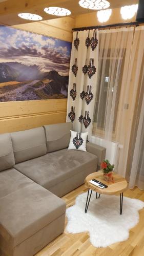 a living room with a couch and a table at Villa Fortuna - Regionalne apartamenty & SPA - Sauna, Grill, Jacuzzi z widokiem na Tatry in Zakopane