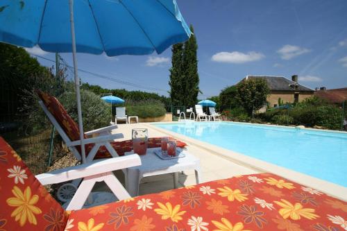 - une piscine avec une table et un parasol bleu dans l'établissement La Vieille Ferme: superbe complexe de 3 gîtes en pierre avec Piscine au coeur du Périgord Noir, à Saint-Geniès