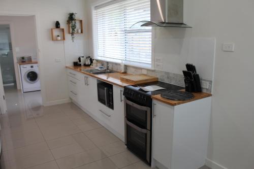 a kitchen with white cabinets and a stove top oven at Rosa's Apartment in Mount Gambier