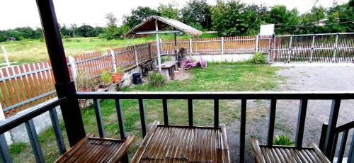 a balcony with two wooden chairs and an umbrella at บ้านสวนยายชุ่ม/bannsuanyaychum in Lampang