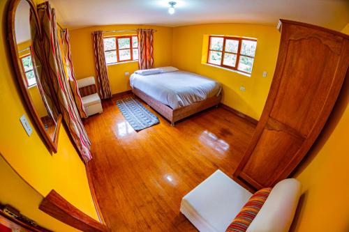 a small bedroom with a bed and yellow walls at Happy Land Valle Sagrado in Urubamba