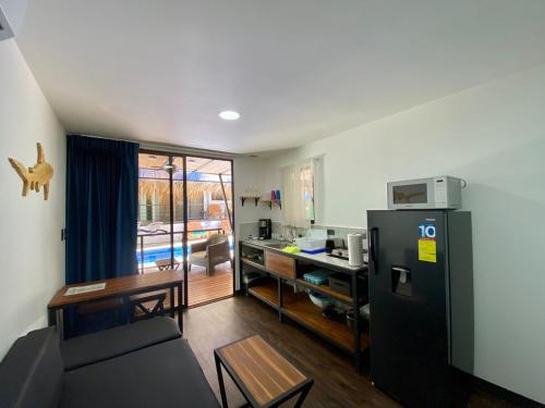 a living room with a refrigerator and a table at Shark Town Mal Pais in Santa Teresa Beach