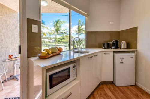 a kitchen with a sink and a microwave at Noosa Sun - On the Noosa River in Noosaville