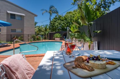 a table with a tray of food and wine glasses next to a pool at Noosa Sun - On the Noosa River in Noosaville