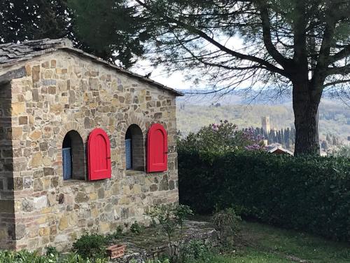 a stone building with red windows and a tree at Il Fiorino di Badia in Badia A Passignano