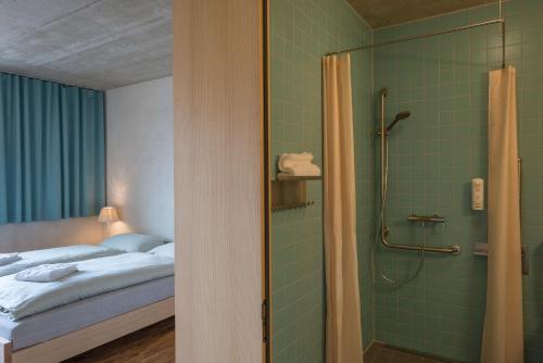 ein Bad mit einem Bett und einer Dusche in einem Zimmer in der Unterkunft Gstaad Saanenland Youth Hostel in Gstaad