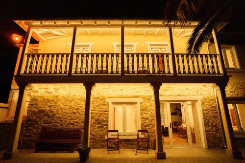 a building with a balcony with two chairs and a table at Apartamentos Minas de Silvarosa in Viveiro