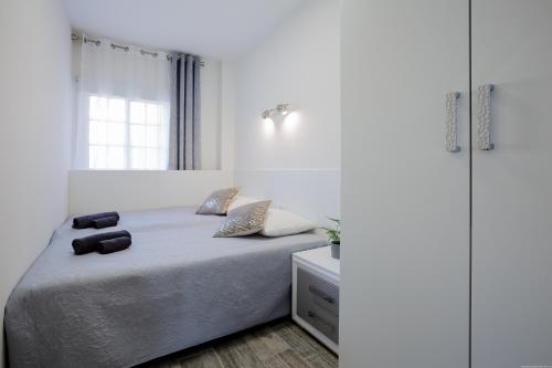 a white bedroom with a bed and a window at Palm Mar de LUX A25 in Palm-mar
