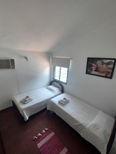 two beds in a room with white walls at Don Carlos Apart in San Miguel de Tucumán