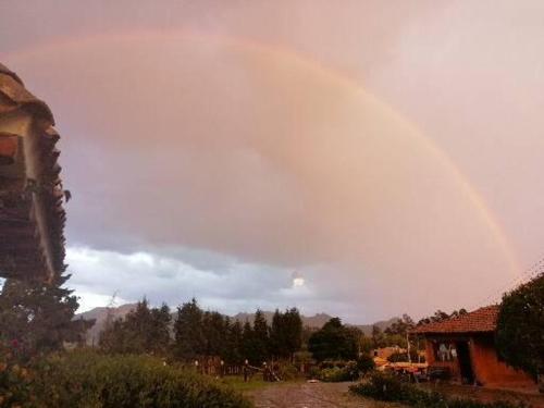 a rainbow in the sky over a house at La Isabela Estancia Ecuestre in Tabio