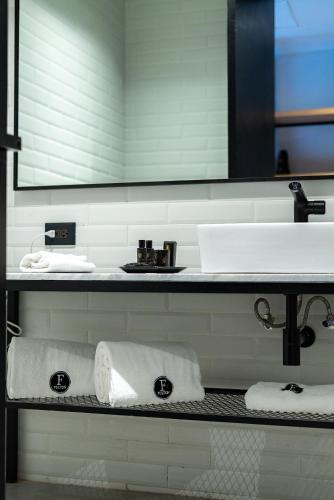 a bathroom with a sink and towels on a shelf at FULTON Business Luxury HOTEL in Guadalajara