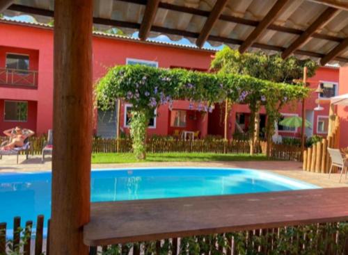 a swimming pool in front of a red house at Village Ecoville das Mangueiras fica a 3km da praia de Guarajuba in Camaçari