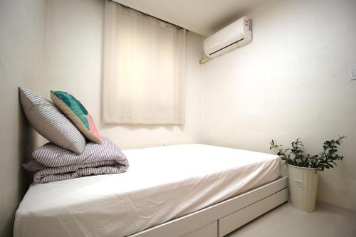 a small bedroom with a bed with pillows and a window at YAB-GuestHouse, FemaleOnly, ForeignOnly in Seoul