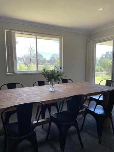 a large wooden table with chairs in a room with windows at Stones Throw Hunter Valley 3mins to Cellar Doors in Cessnock