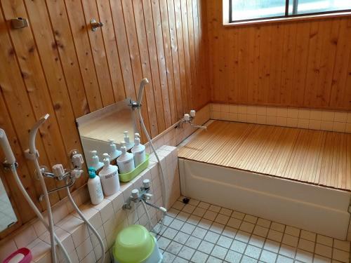 a bathroom with a tub and a toilet in it at Guesthouse Aozora Blue Sky in Myoko
