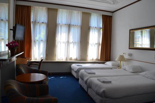 a hotel room with two beds and a table and chairs at Hotel de Munck in Amsterdam