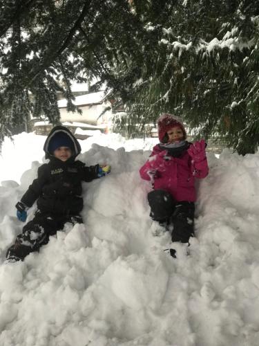two children are sitting in a pile of snow at Maison Laurent in Courmayeur