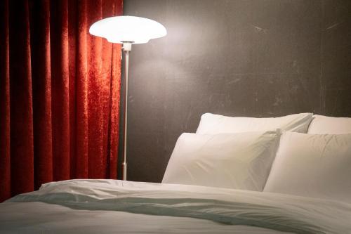 a bed with a lamp next to a red curtain at Shourin Hotel Cheonan by Aank in Cheonan