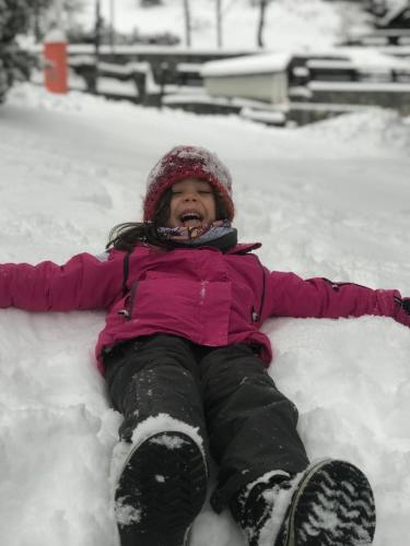 a child is laying in the snow at Maison Laurent in Courmayeur
