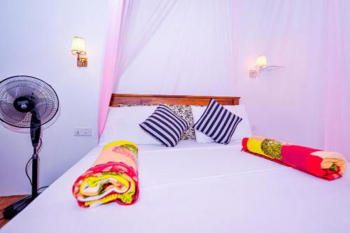 a bedroom with a white bed with a fan at Astral Zone Cottage ELLA in Ella