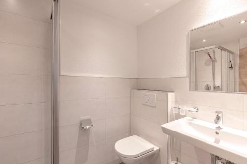 a white bathroom with a toilet and a sink at Apart Felsenhof in Längenfeld