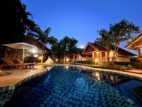 a swimming pool in front of a house at night at Siri Lagoona Resort in Nong Prue