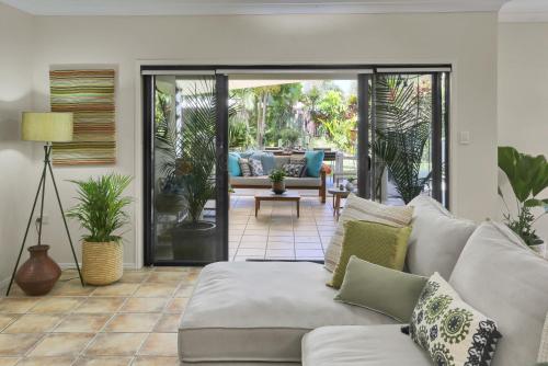 a living room with a couch and a patio at Villa Blue - Coastal Family Escape in Palm Cove